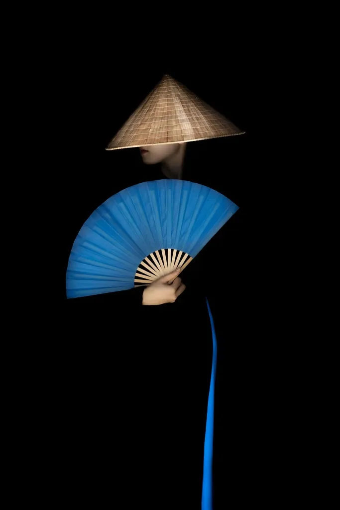 A lady with blue fan wearing black and blue ao dai in Vietnam