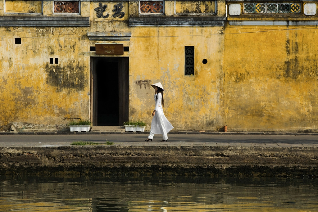 Tradition – Étudiante en Ao Dai blanc à Hoi An, photo de Réhahn Jeune étudiante vietnamienne en Ao Dai blanc marchant le long d’un mur jaune à Hoi An – œuvre Tradition par Réhahn