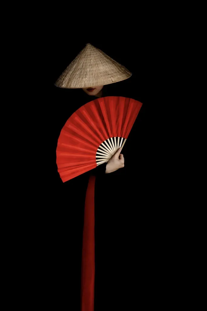 A lady with red fan wearing black and red ao dai in Vietnam