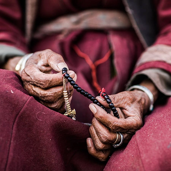 elderly hands holding buddhist prayer beads in Ladakh India